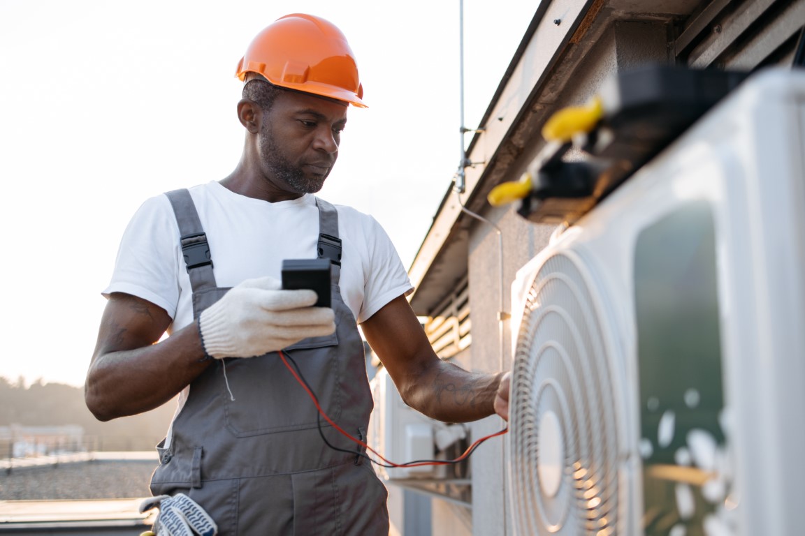 Busy repairman checking voltage level in air conditioner