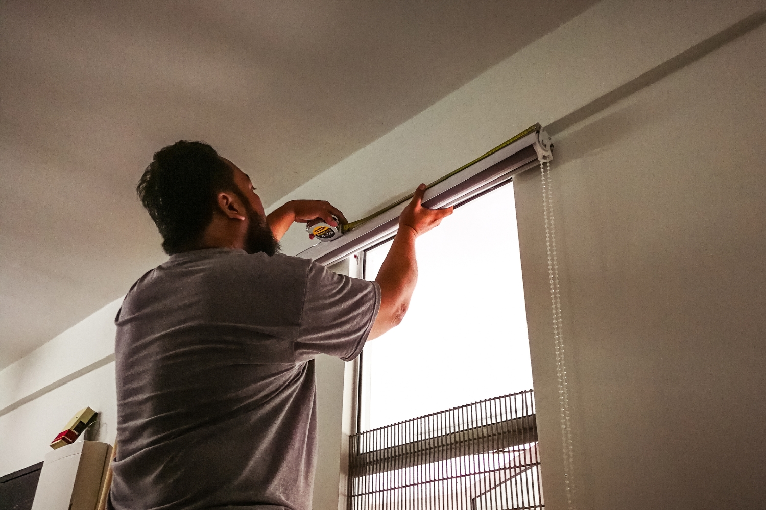 man hanging blinds to reduce heat in home