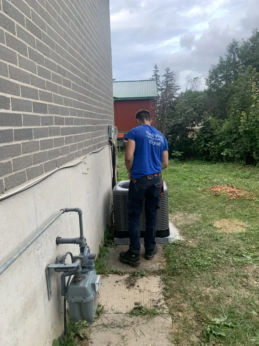 NorthWind HVAC technician servicing an outdoor air conditioner unit beside a Toronto GTA home