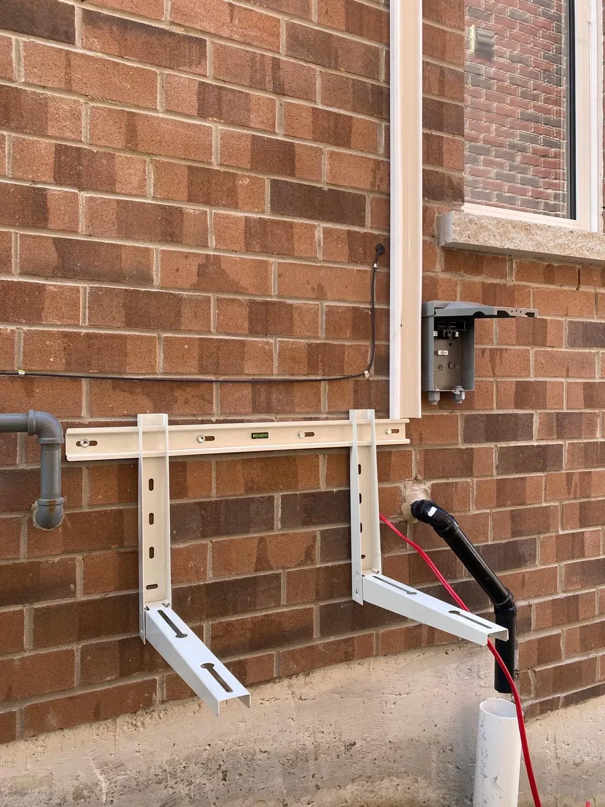 Wall brackets, drain pipe and electrical disconnect installed before mounting the heat pump