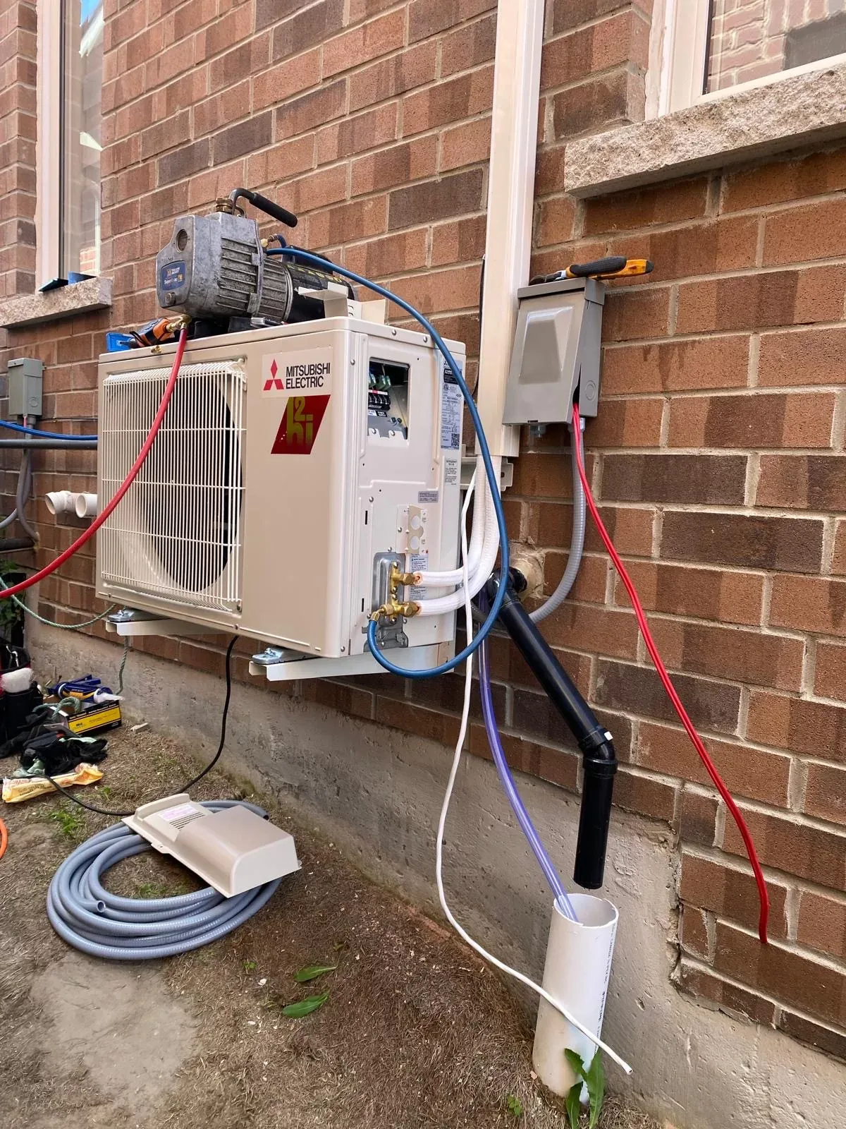 Vacuum pump connected to a new Mitsubishi heat pump outdoor unit during commissioning in Innisfil